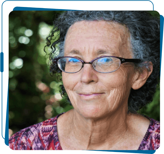 A woman with curly hair wearing glasses and smiling.