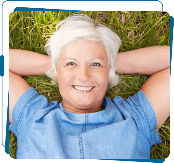 A woman laying in the grass with her hands behind her head.