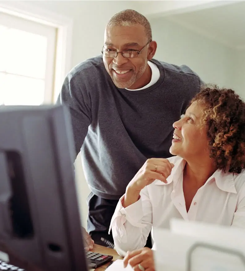 A man and woman looking at the computer screen.