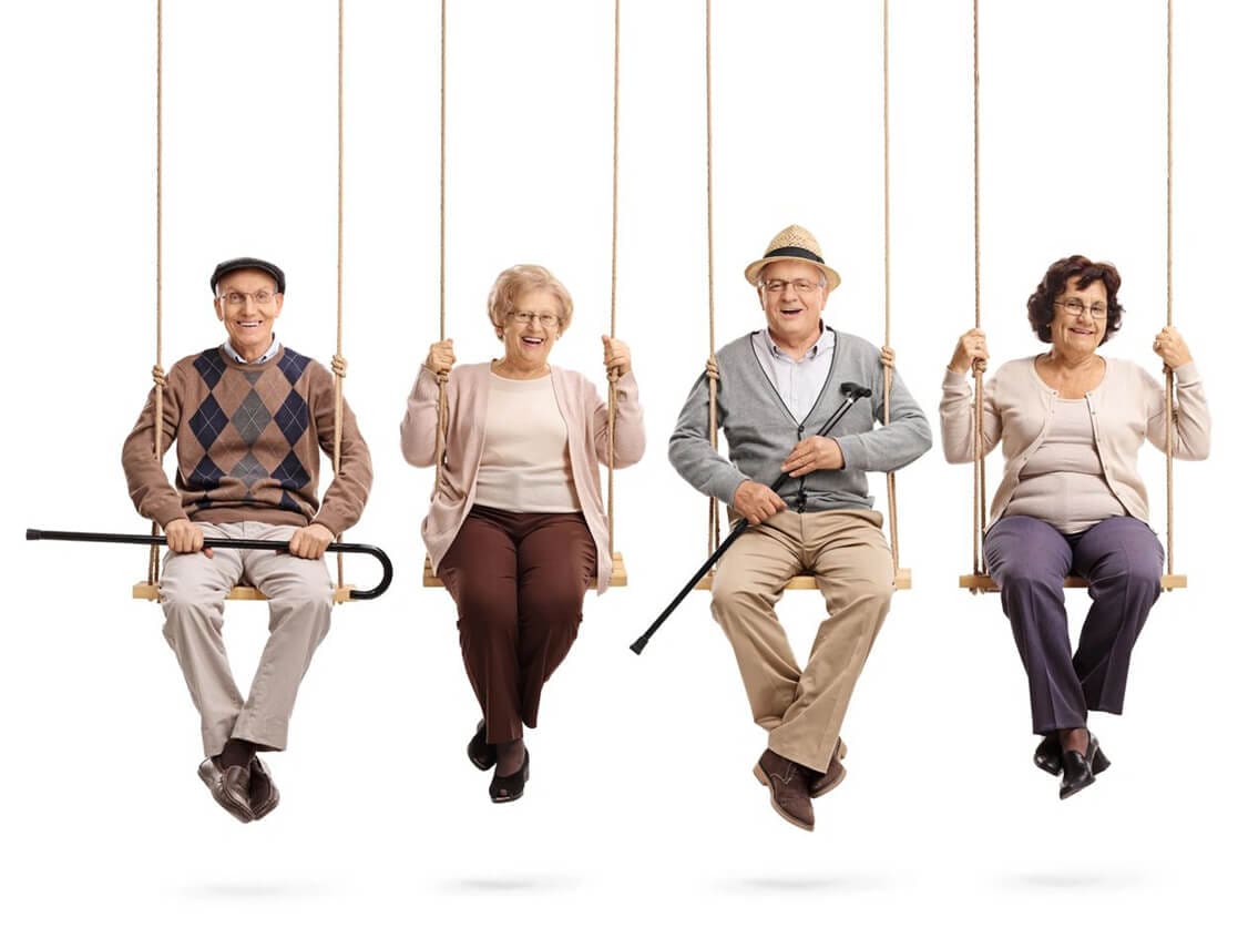 A group of people sitting on swings with one swinging.